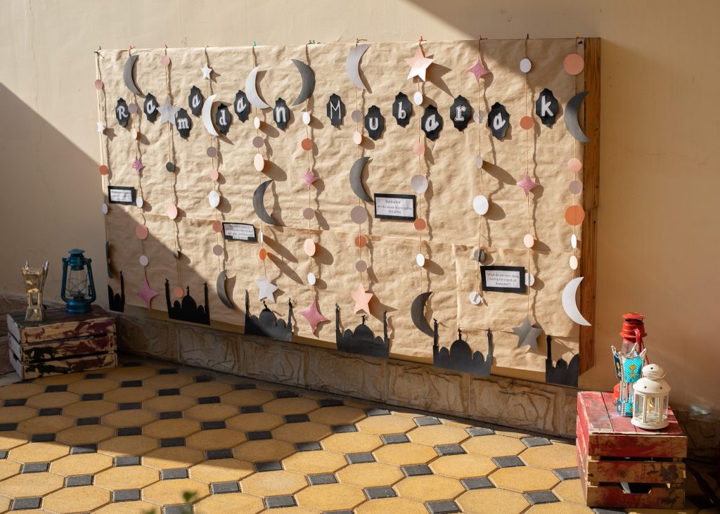Ramadan themed wall display with hanging moon and star paper crafts made by children