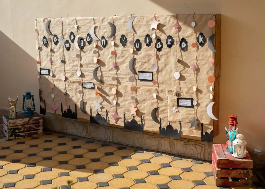 Ramadan themed wall display with hanging moon and star paper crafts made by children