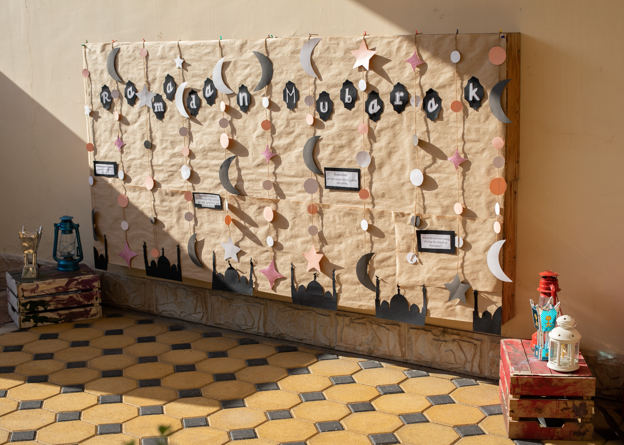 Ramadan themed wall display with hanging moon and star paper crafts made by children