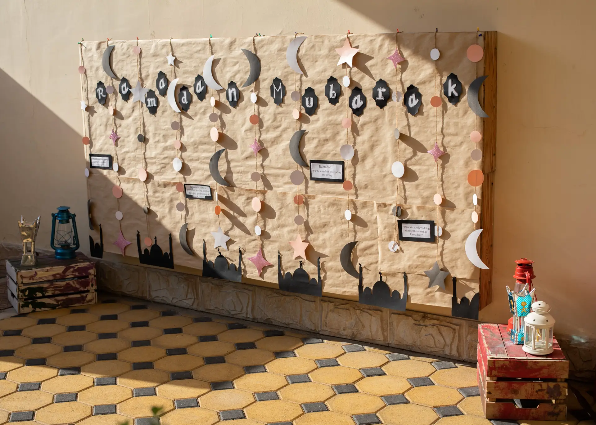 Ramadan themed wall display with hanging moon and star paper crafts made by children