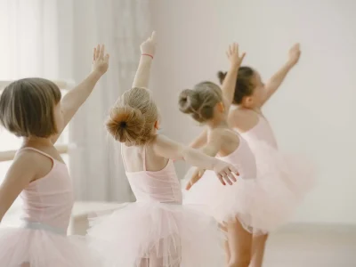 Cute little ballerinas in pink ballet costume. Children in a pointe shoes is dancing in the room. Kid in dance class.
